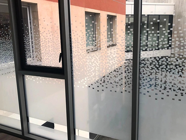 Film adhésif design à motif pixel posé par Énergère sur les vitrages d'un ERP.