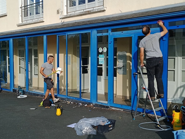 Des collaborateurs d'Énergère préparent des vitrages de l'entreprise à recevoir du film adhésif de protection solaire.
