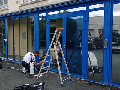 Un collaborateur d'Énergère pose du film adhésif de protection solaire sur les vitrages de l'entreprise.